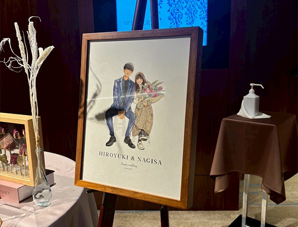 先日無事に結婚式を挙げられましたので、ご報告したくご連絡いたしました。

フジエ様に描いていただいた、新郎新婦2人の似顔絵はウェルカムスペースに飾らせていただき、
それぞれの家族の似顔絵は両親贈呈で渡すことができました。

贈呈する際、せっかくならばとスクリーンで大きく写しゲストにもみていただいたのですが、
「うわあああ、すごい」「めちゃくちゃいいね」など歓声が上がっておりました。

新婦母はもちろんですが、新郎母もすごく喜んでくださり、早速玄関に飾っているそうです。
改めてお礼を申し上げたく、ついメールをお送りしました。

本当にありがとうございました。